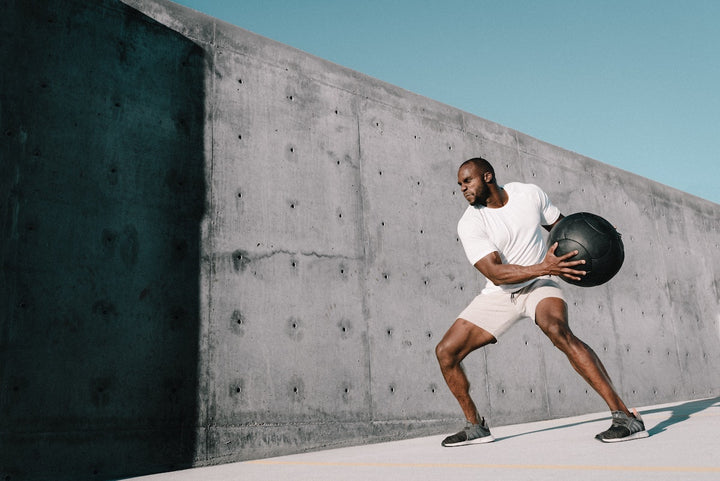 A man uses ketone fuel to work out with a large medicine ball